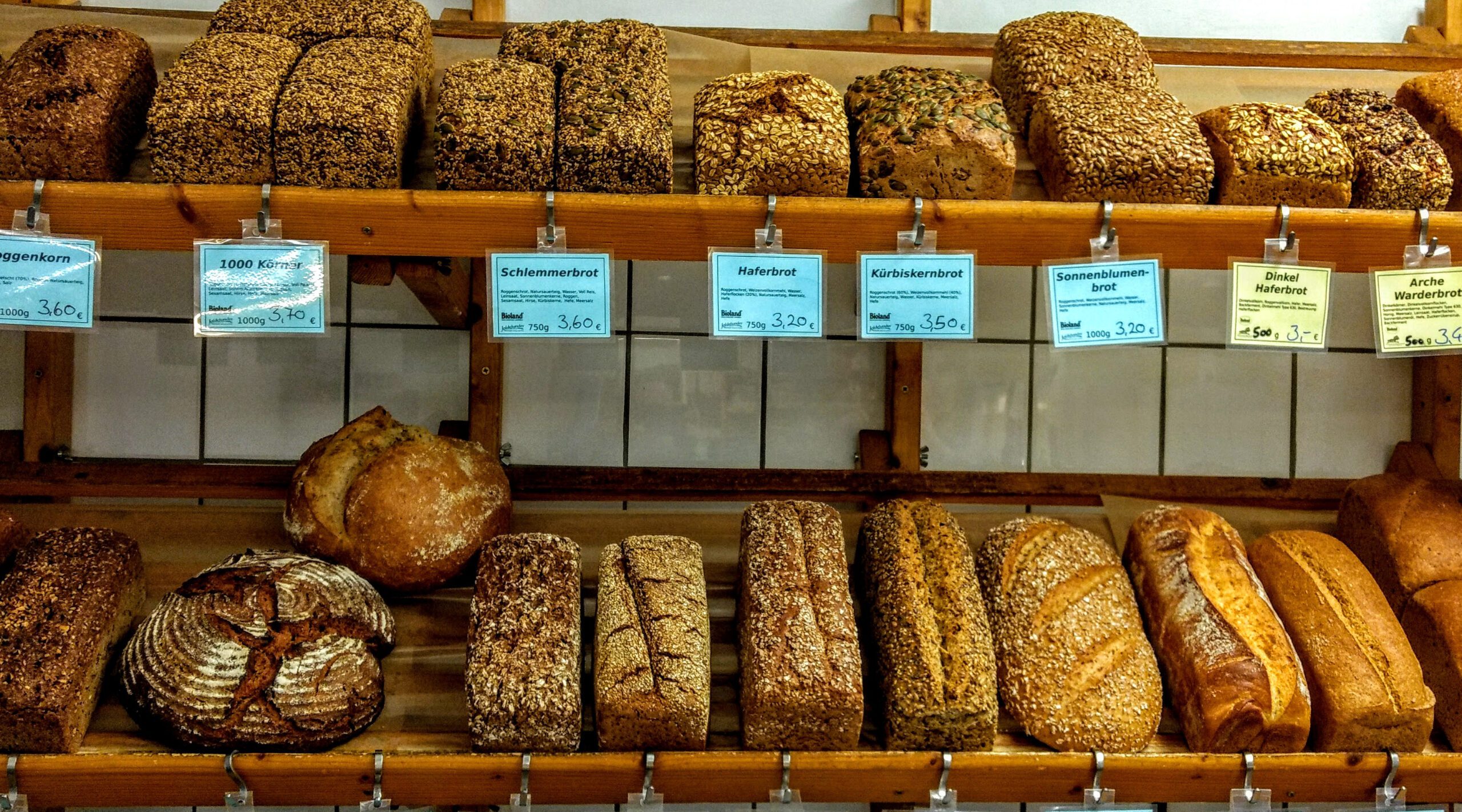 Frisches Bio-Brot in verschiedenen Sorten, ordentlich auf Holzregalen im Mitgliederladen des BioHofs Kiel präsentiert.