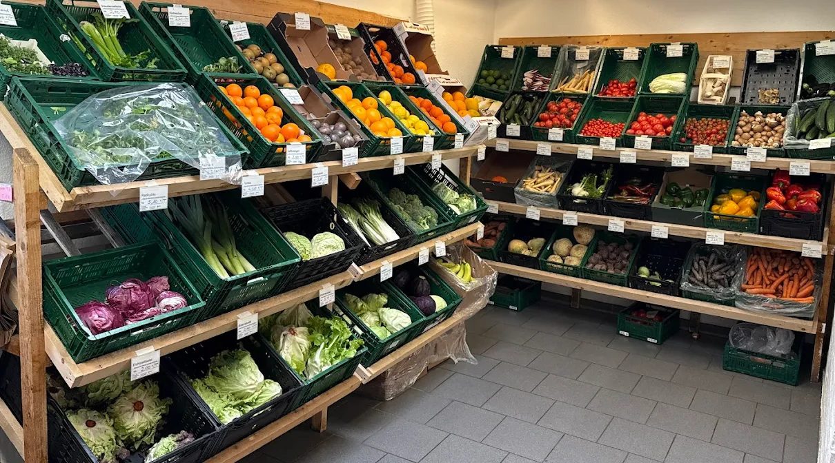 Regal mit saisonalem Bio-Gemüse und Obst im Mitgliederladen des BioHofs in Kiel – bunte Vielfalt in grünen Kästen.