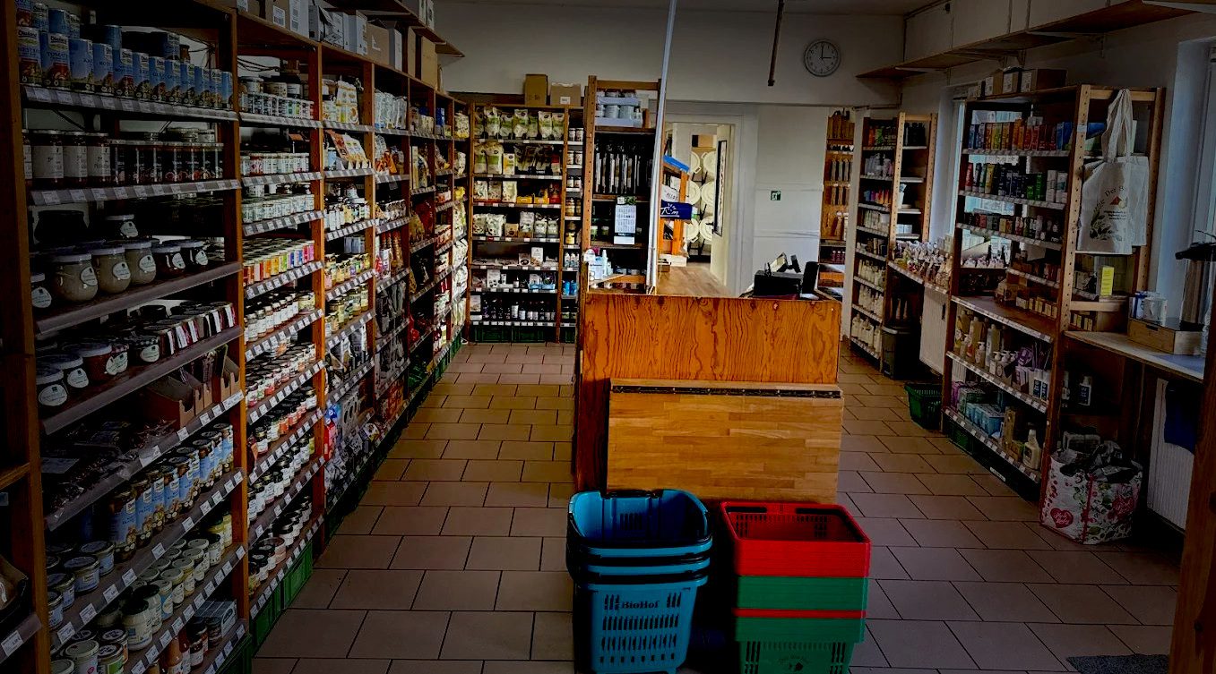 main (1) Innenansicht des BioHof-Mitgliederladens in Kiel mit Holzregalen voller regionaler Bioprodukte und gemütlicher Atmosphäre.